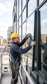 Professional glazier installing glass panel on a modern high-rise facade
