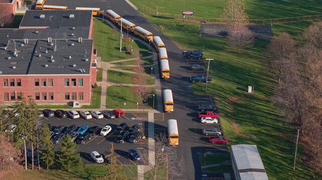 Drone view of yellow school buses lined up for student pickup at an American school