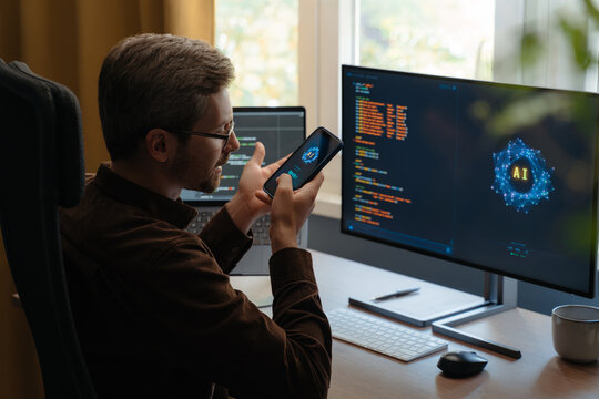 Programmer communicating with an AI agent through a smartphone, using a voice digital assistant on phone for software development and vibe coding. Man talking with Artificial intelligence powered app
