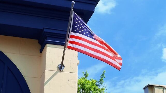 Low angle vertical shot of the United States flag waving in the wind against a clear blue sky