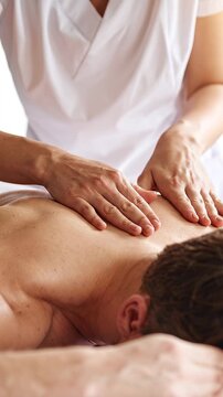 Manos de masajista profesional dando un masaje en la espalda de un cliente
