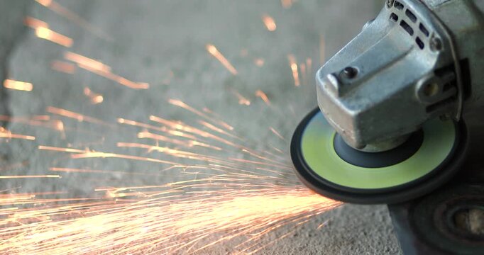 Worker using an angle grinder to cut metal with flying sparks. metalworking, industrial manufacturing, construction, fabrication, maintenance, engineering, and workshop concepts, close-up