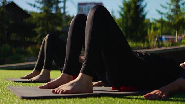 Elderly women practicing gentle Pilates in slow motion on outdoor mats, using massage rollers to support mindful stretching, balance, and low-impact core strengthening