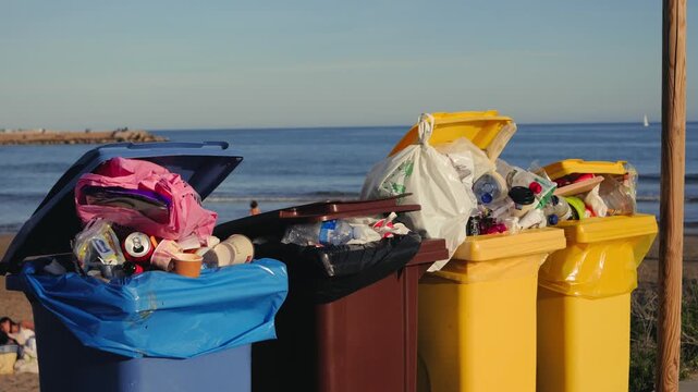 Bins filled with plastic and organic waste on a beach with the sea in the background. Recycling, waste sorting, environmental protection and sustainable lifestyle concept. High quality 4k footage