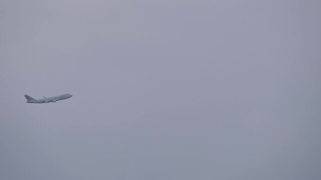 Large cargo airplane, airliner is flying in the gray sky, overcast, slow motion. Industrial, logistics and transportation concept