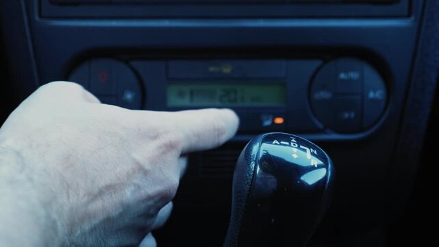 Driver testing car air conditioning ON and OFF button