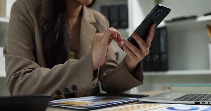 Businesswoman using a smartphone to review financial information, manage business communication, and access digital reports in a modern office, supporting mobile productivity and business management.