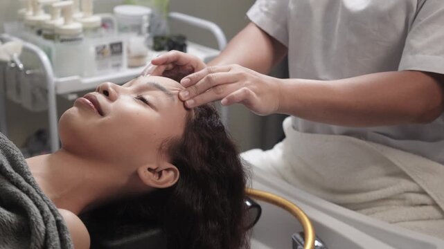 A young filipino woman receives a head massage before a Japanese hair spa at a salon.