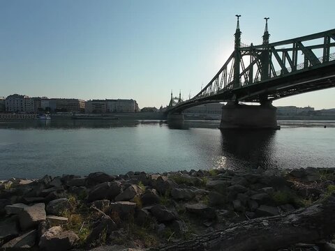 Low water level of the Danube river in Budapest at sunrise, featuring the Liberty Bridge and the uncovered Inseg Rock, and the Margit bridge and the island. 02.08.2026.