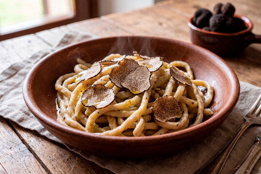 Traditional handmade Italian stringozzi pasta with shaved black truffle in a rustic bowl