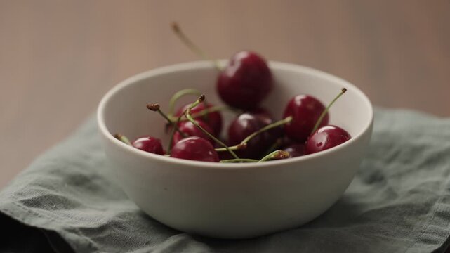 Slow motion serving fresh cherries in white bowl