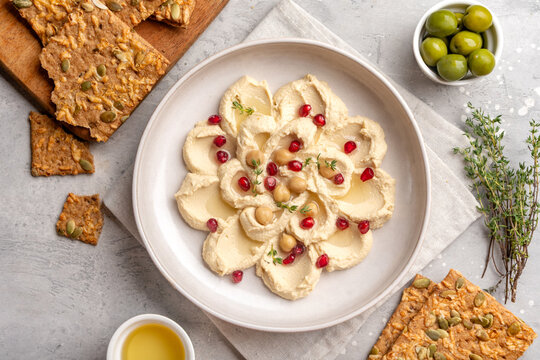 Creamy Hummus Bowl With Pomegranate Seeds, Chickpeas, Olive Oil and Rustic Bread