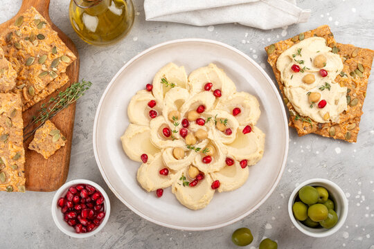 Creamy Hummus Bowl With Pomegranate Seeds, Chickpeas, Olive Oil and Rustic Bread