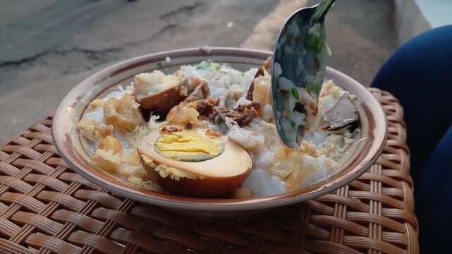 Chicken porridge with a full complement of toppings: shredded chicken, a hard-boiled egg, chicken liver and gizzard, and a sprinkle of peanuts. A favorite Indonesian street food for breakfast