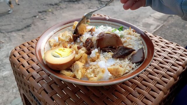 Chicken porridge with a full complement of toppings: shredded chicken, a hard-boiled egg, chicken liver and gizzard, and a sprinkle of peanuts. A favorite Indonesian street food for breakfast