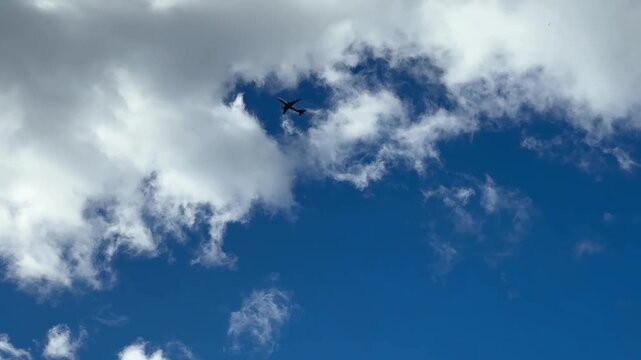 Split, Croatia - October 07, 2025: Airplane flying through a blue sky with scattered clouds, transitioning to a close-up of green leaves against a cloudy backdrop
