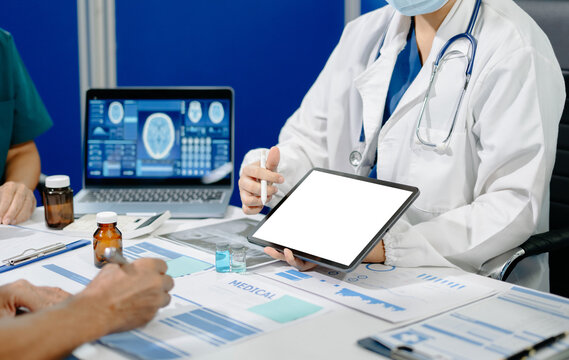 Asian medical team reviews clinical data, medication samples and digital reports during a healthcare meeting, highlighting collaboration, research and medical innovation.