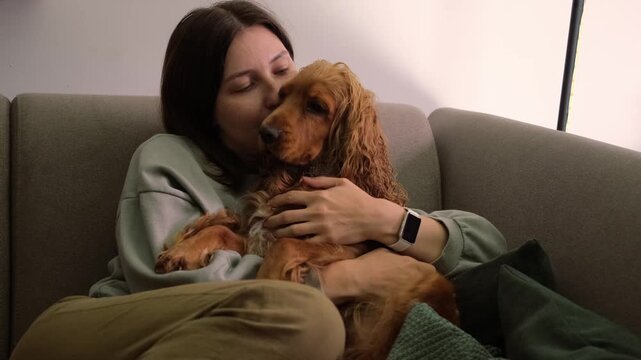 Calm woman hugging her cocker spaniel dog while resting on couch