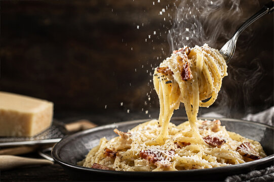 Spaghetti carbonara lifted by fork with grated parmesan