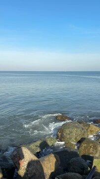 Calm blue sea with rocky shore and clear sky horizon