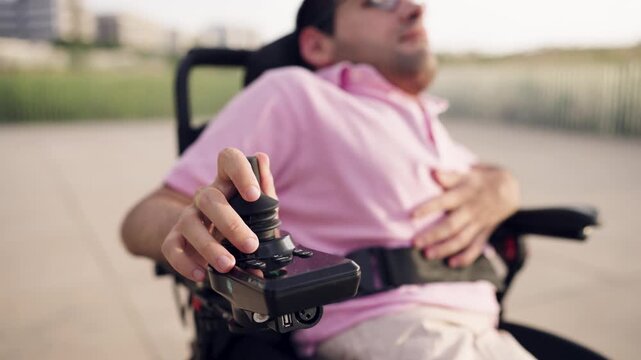 Man with a physical disability using the joystick to drive his motorized wheelchair. Independent person with spina bifida moving freely outdoors