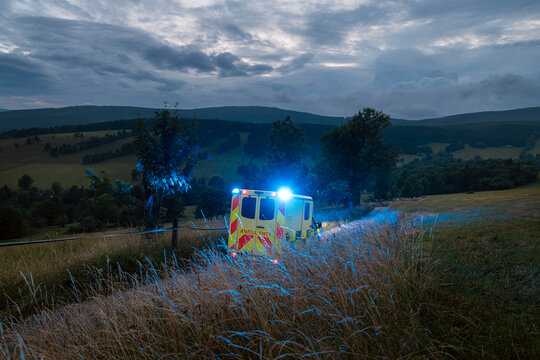 Emergency medical service ambulance vehicle driving on mountain road during twilight. Remote area rescue mission, urgent healthcare response and medical transport concept.