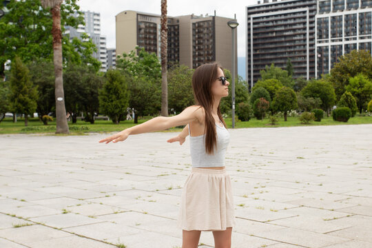 teenage athlete performs a standing shoulder opening stretch in a city plaza, demonstrating warm up, posture care and outdoor fitness before a simple outdoor training session