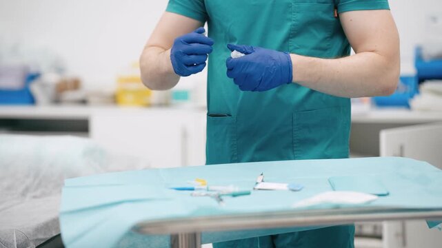 Medical assistant in blue gloves preparing a sterile IV catheter at a surgical tray, getting ready for a medical procedure in a hospital room