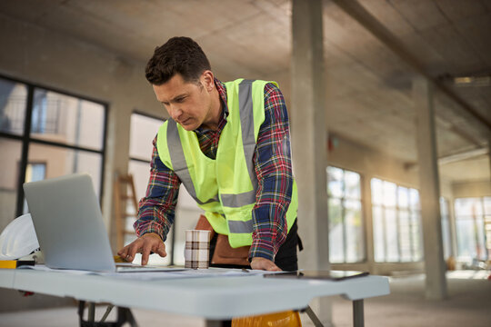 Civil engineer working on a computer at construction site.