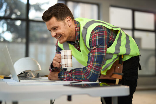Happy manual worker analyzing housing project on a computer during home renovation process