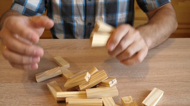 A man tosses wooden blocks that fall onto the table surface with a distinctive wooden knocking sound. The video contains clean original audio.