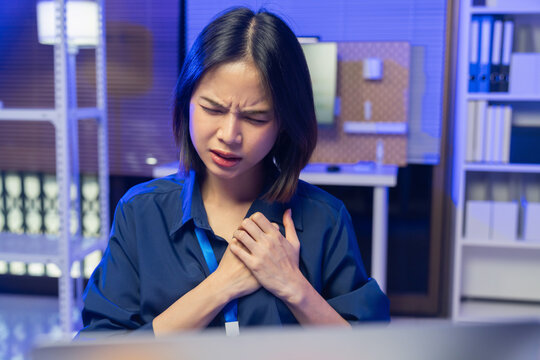 Young Asian businesswoman experiencing chest pain while working in office, health problem and workplace stress concept