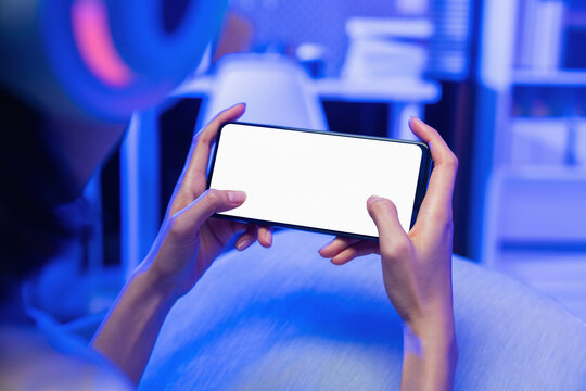 Hands holding smartphone with blank screen while playing mobile game, online gaming and digital entertainment concept.