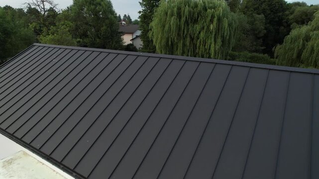 Drone flying over a modern house with black standing seam metal roof
