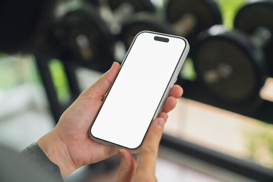 Person using smartphone with blank screen at gym.