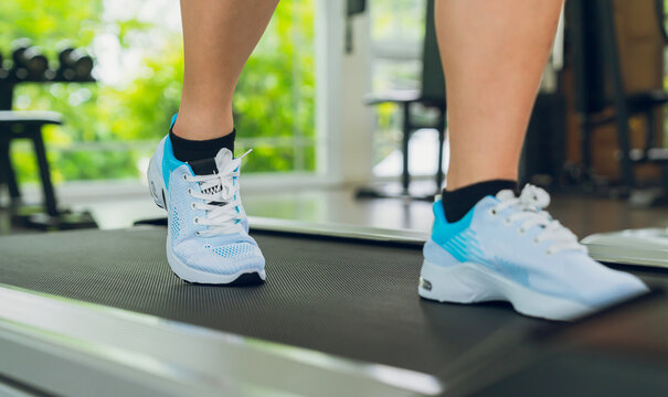 Woman walking on treadmill during indoor workout.
