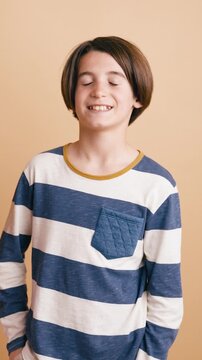 Cheerful tween boy with a stylish haircut wearing a striped shirt. He is looking at the camera and smiling, showing genuine happiness. Vertical