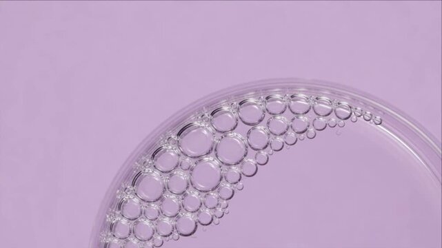 Cinematic macro liquid texture background with bubble circle pattern minimal clean science aesthetic pastel abstract art design creating calm purity mood on soft violet surface
