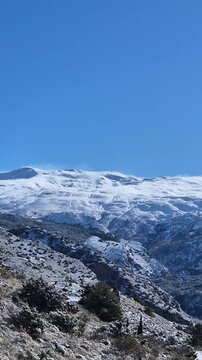 Unrecognizable person hiking on a beautiful snowy day in the mountains of Sierra Nevada, Spain. Clear blue sky on a winter day