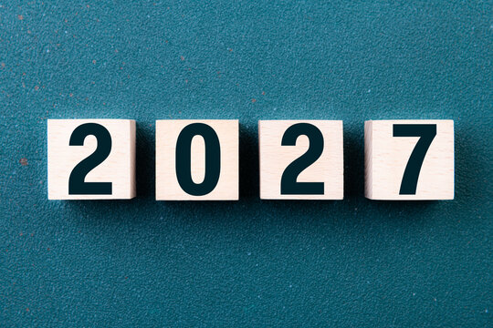 2027 Happy New Year. Wooden cube block 2027 greeting card on green. Concept 2027 New Year background. Business, resolutions, goals, inspiration, success, ideas