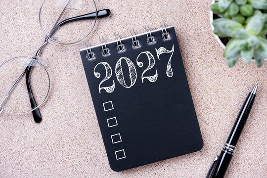 New year goals 2027. 2027 resolutions list with notebook, coffee cup, plant on table. Resolutions, plan, goals, action, checklist, idea concept. New Year 2027 resolutions, copy space