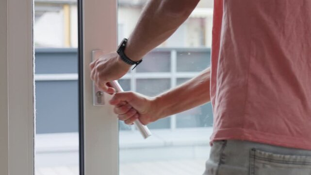Man opening terrace door by pulling metal handle with both hands