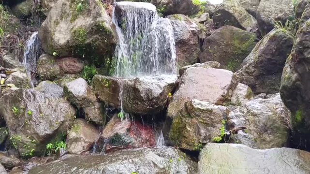 Cascading Waterfall Flowing Over Wet Mossy Rocks in Nature