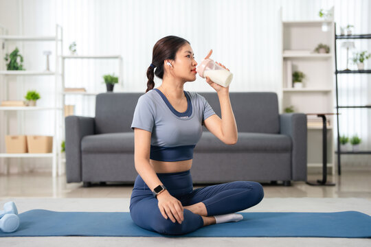 Asian woman drink whey protein shake  diet food after home workout.