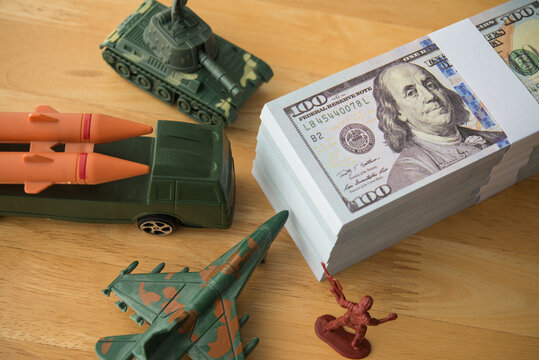 US banknotes, army solider, combat aircraft fighter, tank, missile on wooden table. U.S. military spending or defense budget, research and development, maintenance, procurement, peacekeeping concept.