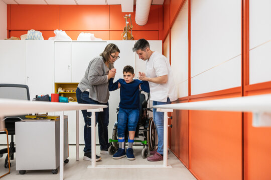 Child learning to walk with orthosis in physical therapy