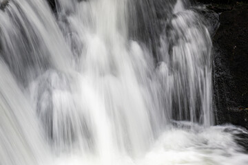 Cascading water flowing over dark rock in close-up © Philip