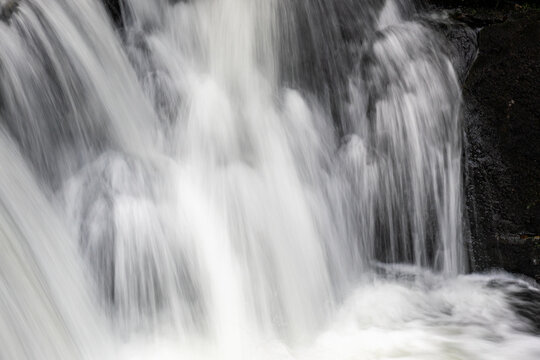 Cascading water flowing over dark rock in close-up