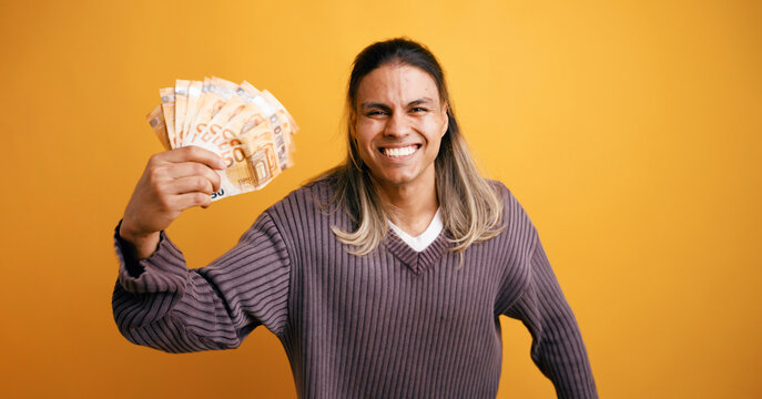 Happy latino man smiling, holding a fan of fifty euro banknotes, expressing financial success and wealth
