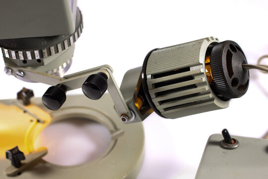 Close-up of the external illuminator mounted on a vintage stereo microscope. Adjustable laboratory lighting system isolated on a white background.